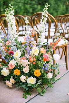 an arrangement of flowers on the ground in front of chairs