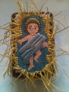 a cross - stitch picture of the virgin mary holding a baby jesus in a straw basket