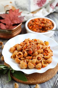 pasta with meat and vegetables on a white plate next to other food in small bowls