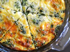 a close up of a pizza on a pan with cheese and spinach toppings