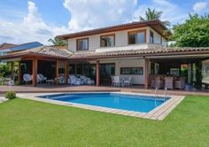 a house with a swimming pool in front of it and some chairs around the pool