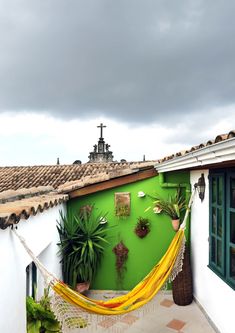 a hammock hanging from the side of a building with potted plants on it