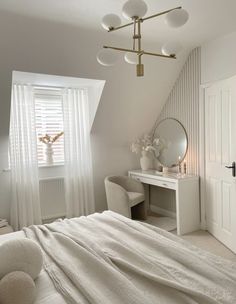 a bedroom with a bed, desk and mirror in the corner next to a window