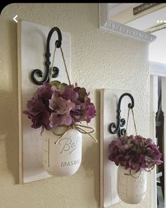 two mason jars with flowers hanging on the wall