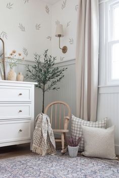 a white dresser sitting next to a window in a room with a rug on top of it