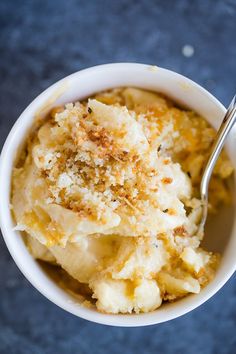 a bowl filled with macaroni and cheese on top of a blue tablecloth