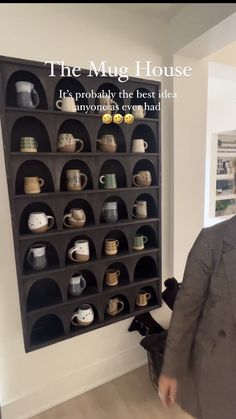 a man standing in front of a shelf filled with cups and mugs on it