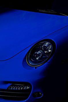 the front end of a blue sports car with its lights on and headlight up