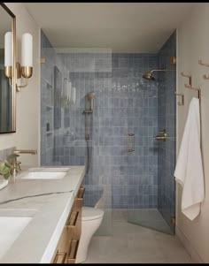 a bathroom with blue tile and gold fixtures on the walls, along with a walk in shower