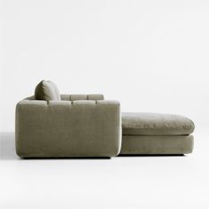 a couch and ottoman sitting next to each other in front of a white wall with no one on it