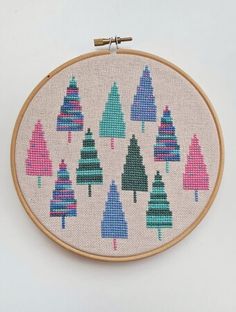 a cross stitch pattern with colorful trees on the front and back, hanging from a wooden hoop