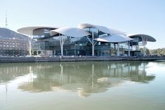 a large building sitting on the side of a river next to a tall white structure