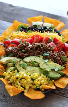 a platter filled with corn, avocado, tomatoes, black olives and other veggies