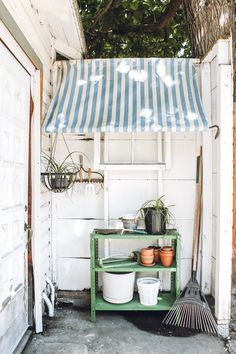 a green shelf with potted plants under a blue and white awning over it