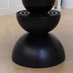 two black vases sitting on top of each other in the middle of a room