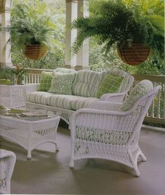 an outdoor living room with wicker furniture and potted plants on the porch area