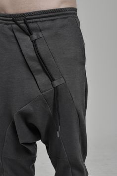 "DISTORTED ANTHRACITE DROPPED CROTCH TRACK PANTS WITH ELASTIC WAISTBAND __ELASTIC WAISTBAND WITH DRAWSTRING __J SHAPED LEGS __2 FRONT POCKETS __2 REAR BONDED POCKETS __ASYMMETRICAL HIDDEN FRONT CLOSURE model__ chest 103 (40.5\"), waist 77 (30.3\"), hips 96 (37.8\"), biceps 35 (13.8''), height 180 (5'11\"), kg 74 (163 lbs) model wears size S | color: anthracite with black matte tape fabric__ 100 cotton care__ delicate machine wash at 30 c wash inside out use cool iron do not tumble dry sizing__ s Futuristic Pants, Urban Clothing Men, Low Crotch Pants, Sporty Leggings, Winter Tights, Track Pants Mens, Drop Crotch Pants, Mens Tights, Grey Blouse