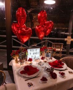 the table is set for valentine's day with red balloons