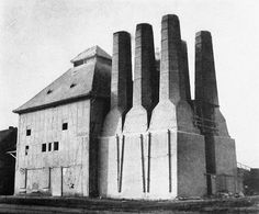 an old black and white photo of a building made out of cement blocks with large chimneys