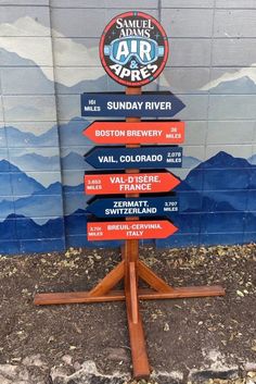 a wooden sign sitting on the side of a building next to a blue and white wall