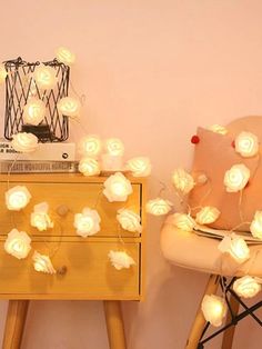 two chairs with flowers on them next to a night stand and lamp in the corner