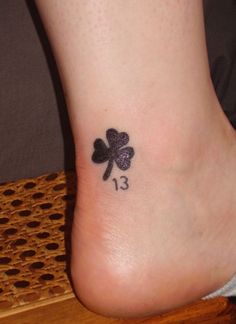 a small four leaf clover tattoo on the left side of the foot, which reads 13