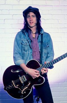 a man with long hair holding an electric guitar