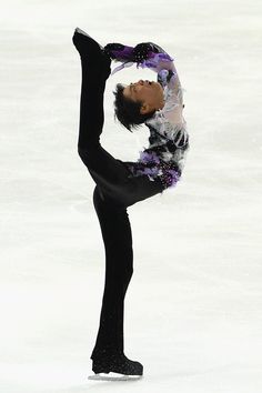 a female figure skating on the ice in a black outfit with purple and white flowers