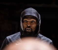 a man with a hoodie on looking at something in front of him and his reflection