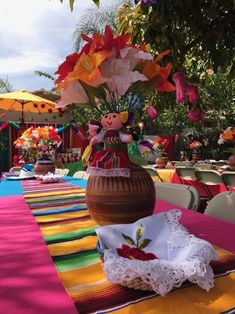 a vase with flowers in it sitting on top of a colorful table cloth at an outdoor event