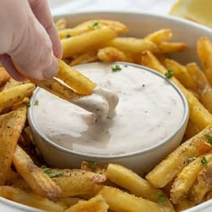 a person dipping some fries into a bowl