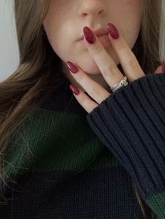 a close up of a person wearing a sweater and holding their hand to her mouth