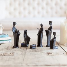 small black figurines sitting on top of a wooden table next to a candle