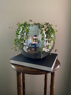 a mirror ball sitting on top of a wooden table next to a book and plant