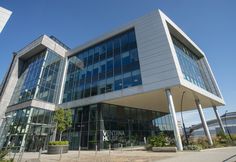 an office building with large glass windows on the front and side of it's facade