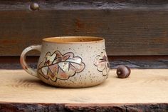 a ceramic cup with flowers painted on it and a snail sitting next to the cup