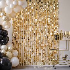 some balloons are in front of a gold and white backdrop with black and white balls