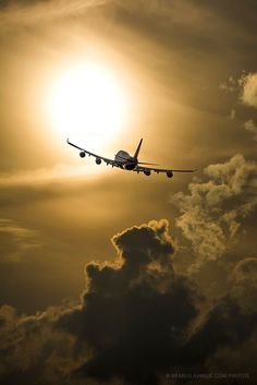 an airplane is flying in the sky at sunset or dawn with clouds and sun behind it