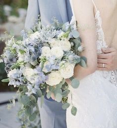 a bride and groom standing next to each other holding their wedding bouquet in their hands