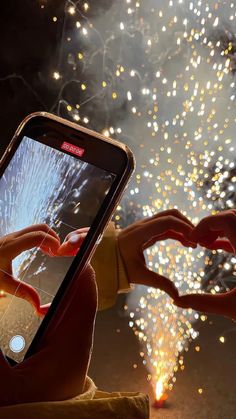 someone taking a photo with their cell phone while fireworks go off in the background