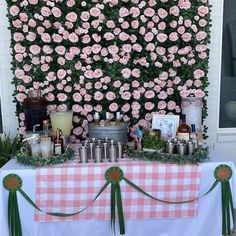 a table topped with lots of food and drinks next to a wall covered in flowers