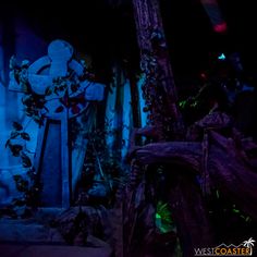 a statue is lit up at night in the dark with blue lights and green foliage