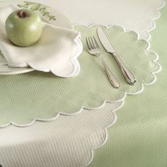 an apple sits on a plate next to a fork and knife, along with two napkins