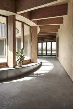 an empty room with large windows and concrete flooring on both sides, surrounded by wood paneling