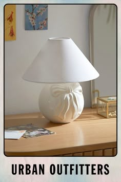 a white lamp sitting on top of a wooden table next to a mirror and pictures