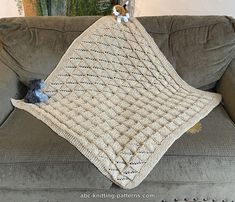 a crocheted blanket sitting on top of a couch next to a stuffed animal