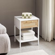 a small white table with drawers and a towel on it next to a bed in a room