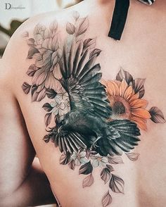 a woman's back with a bird and flowers on it