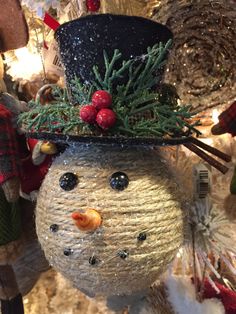 a snowman ornament hanging on a christmas tree with ornaments around it in the shape of a top hat