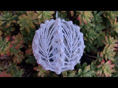 an ornament hanging from a bush with leaves and flowers in the foreground